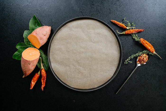 Teglia ricoperta con carta da forno, patata tagliata in due, patate dolci, idee per cena leggera