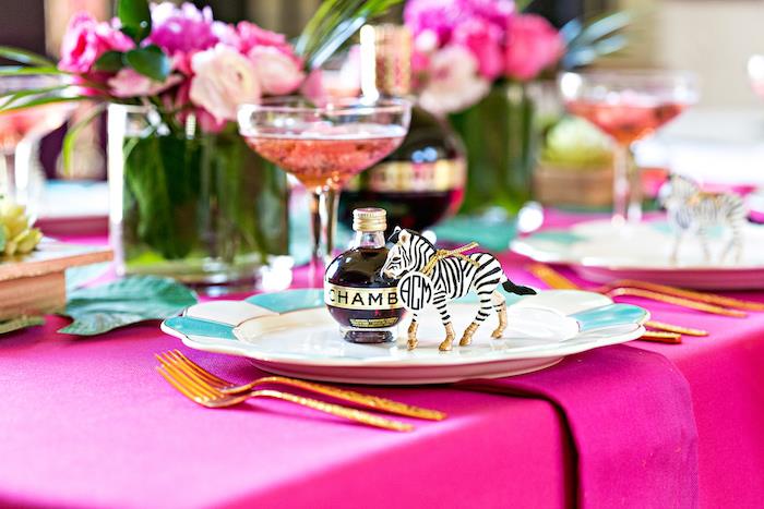 atogrąžų vakarėlio dekoras, rožinės ir fuksijos gėlių pagrindinė idėja, fuksijos spalvos staltiesė, zebros figūrėlės gimtadienio vieta