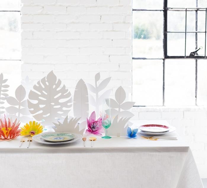 beyaz tropik yapraklar merkez ve renkli kağıt diy çiçek tuğla duvarlı beyaz odada ve beyaz masa örtüsü ile kaplı masa