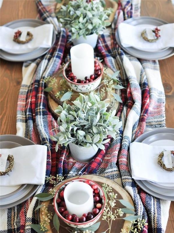 renkli battaniyede merkez parça, saksı bitkileri ve kızılcıklı kaselerde mumlar, masayı süslemek için Noel zanaatı