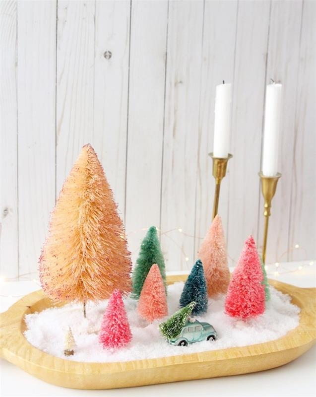originali Kalėdų centro idėja, padėklas su dirbtiniu sniegu, spalvingos Kalėdų eglutės figūrėlės ir auksinės žvakidės