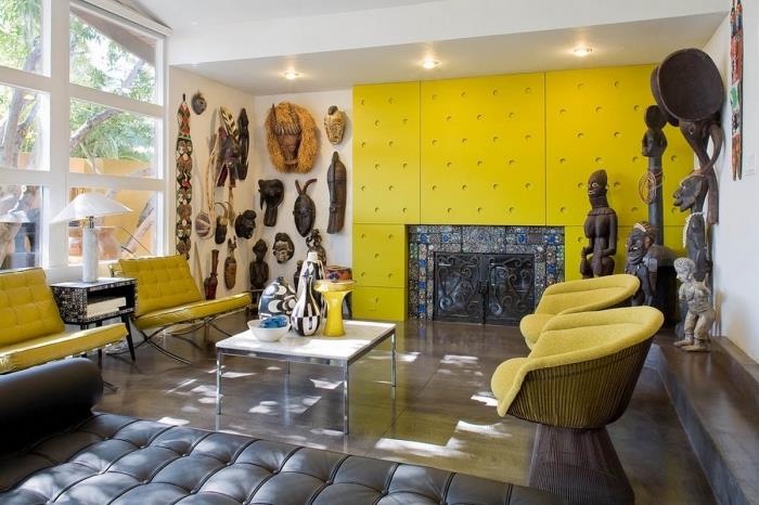 dnevna soba z afriškimi motivi z gorčično rumenimi stenskimi ploščami, skulpturami in plemenskimi maskami