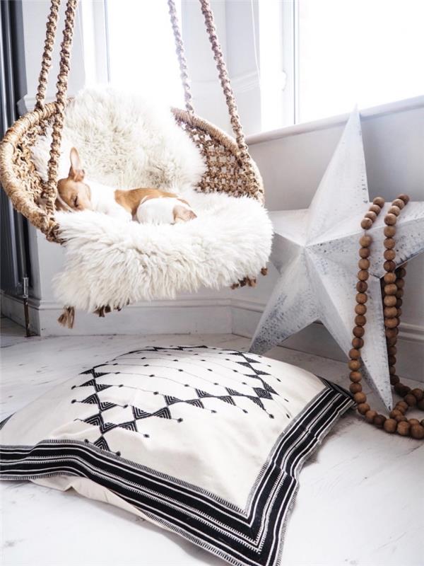 jauki atmosfera boho stiliaus miegamajame su pakabinama kėdė, uždengta baltu dirbtinio kailio užvalkalu