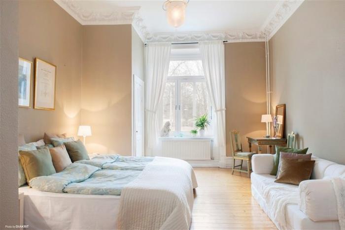 pencere ve beyaz kanepe altında bir tezgah ile genç odası nasıl dekore edilir, boz duvarlı oda ve alçı süslemeli beyaz tavan