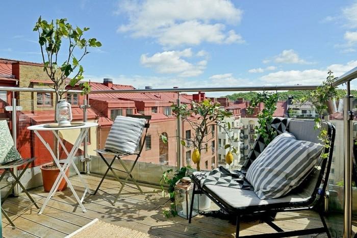 metalinės kėdės ir stalas bei mažas metalinis fotelis, kompozicinės medinės grindys, stiklo turėklai, nedidelis balkono išdėstymas