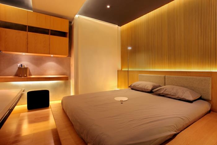 medinė sienų danga, smėlio spalvos lova, romantiškas miegamojo apšvietimas, sieninės lentynos