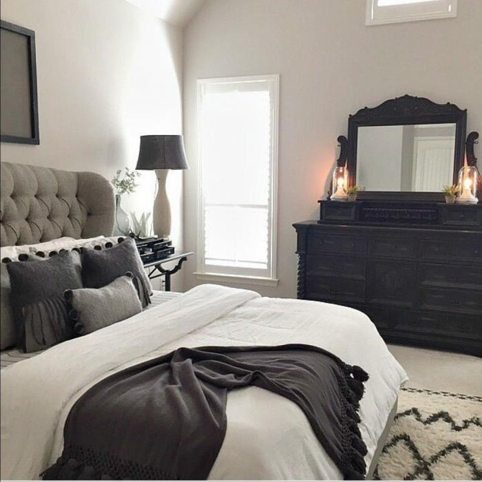 miegamasis pilkos, baltos ir juodos spalvos, balta lova su pilkomis pagalvėlėmis, juodas pledas, elegantiškas veidrodis