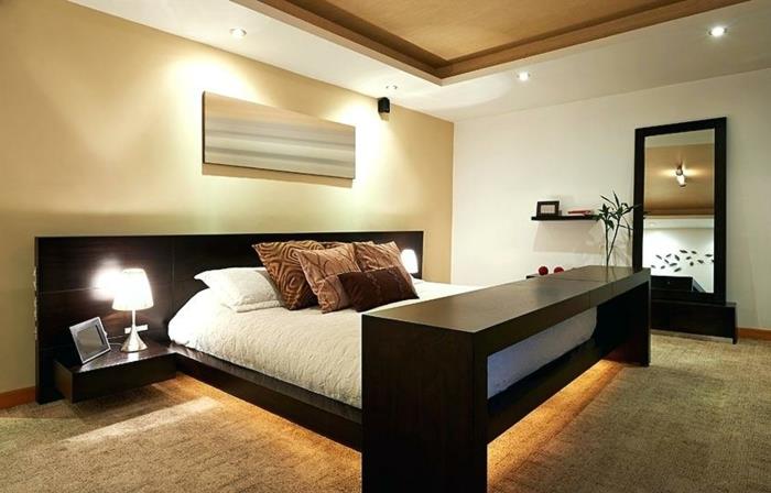 lepa feng shui spalnica v barvi taupe in z leseno posteljo, vgradnimi reflektorji in plavajočimi nočnimi omaricami