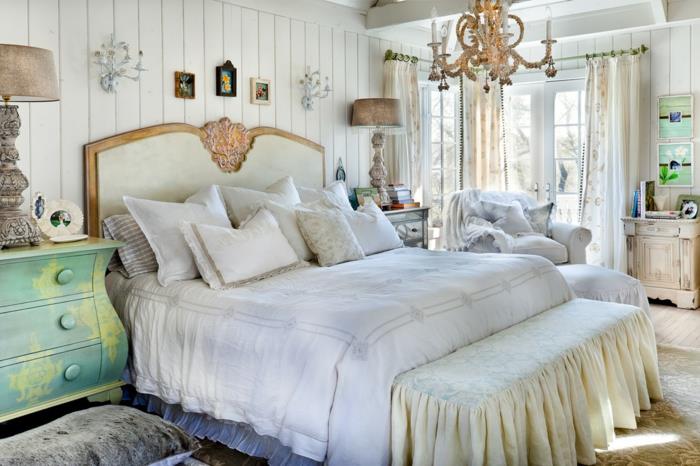 modernus suaugusiųjų miegamojo dekoras, ištaiginga liustra, baltos ir auksinės spalvos galvūgalis, mėtų žalia komoda, balta lentų sienų danga