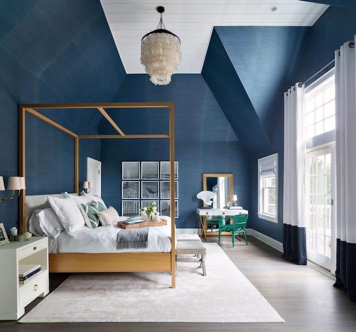 barva spalnice s temno modrimi stenami, originalna viseča svetilka, lesena postelja z baldahinom, bela preproga, siv parket, črno -bel okvir deco
