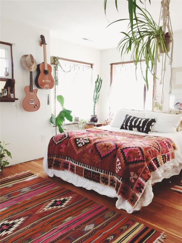 bohem şık bir yatak odası, aynı desenlerden bir battaniye ile kombinlenmiş etnik desenli bir halı