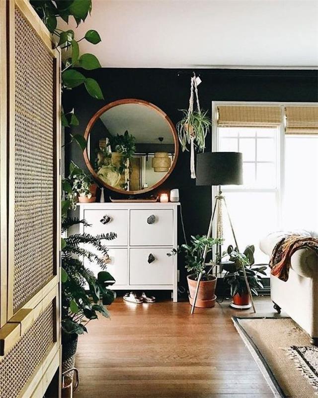 Sodobna notranjost v sobi z veliko zelenimi rastlinami, okroglo ogledalo, svetilka s tremi nogami, bež kavč, žaluzijska preproga, dnevna soba s temno modrimi stenami