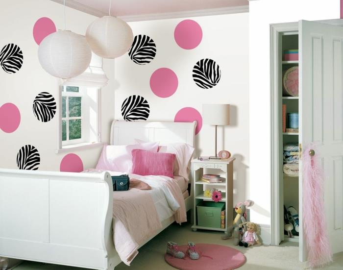 moderna spalnica, ideja za okrasitev spalnice, bele stene z velikimi rožnatimi in črno -belimi pikami, majhna roza preproga, velika omara z belimi vrati, zajčje mehke igrače poleg nočne omare