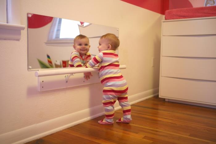 ogledalo na steni za prebujanje otrokovih čutov, postelja montessori v sobi montessori, jaslice brez palic, palica v beli barvi, ki pomagajo otrokovim prvim korakom