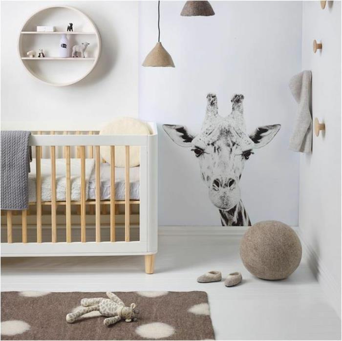 visiškai pigus kūdikio kambarys, medinė ir balta kūdikio lova, apvali lentyna, vienspalvė žirafa ant sienos