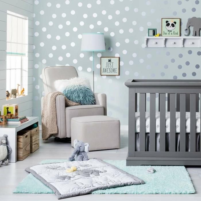 visiškai pigus kūdikio kambarys, pilka kūdikio lova, šviesiai pilkas fotelis, šviesiai mėlynas kilimas