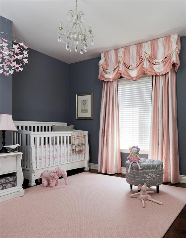 pigus kūdikio kambarys, kutų liustra, rožinės ir baltos užuolaidos, lovelė, pilka išmatos, rožinis kilimas