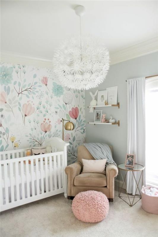 kūdikio mergaitės kambario apdaila, šviesiai rudas aksominis fotelis, rausvas apvalus pufas, balta miegamojo liustra su gėlių raštais, pastelinių tonų gėlių raštų siena