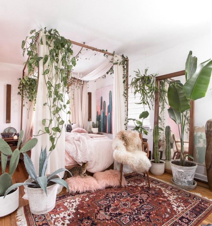 egzotiška atmosfera prašmatniame bohemiškame miegamajame su mediniu lovos rėmu ir žaliais augalais dekoruotu baldakimu