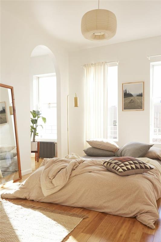 pagrindinio miegamojo dekoro idėja, persikinė patalynė, didelis įrėmintas veidrodis, grafinio rašto pagalvėlės, balti sienų dažai