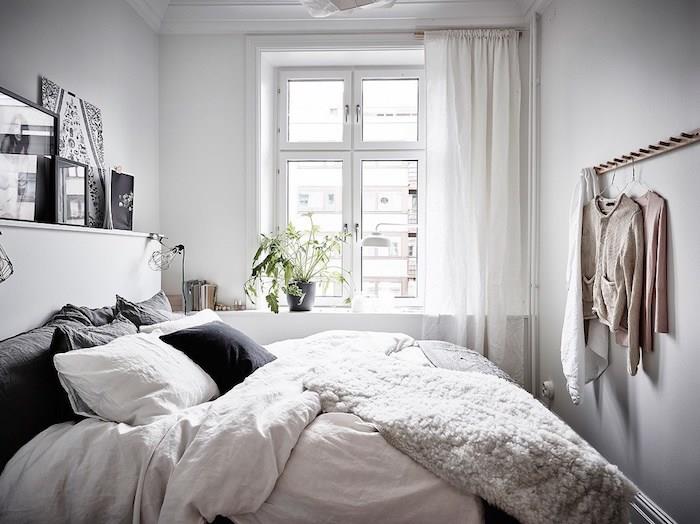 skandinavska blazina, več belih in sivih blazin na postelji z belim posteljnino, puhasta odeja, grafična dekoracija sten