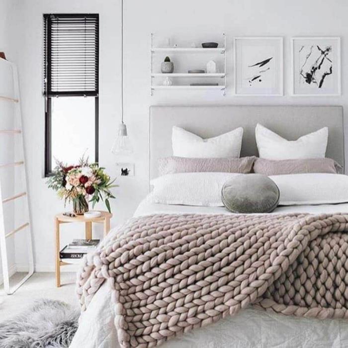 jaukus ir gražus skandinaviško stiliaus miegamasis, pilkai megztas pledas, kailinis kilimas, baltos kopėčios, paveikslų rėmas