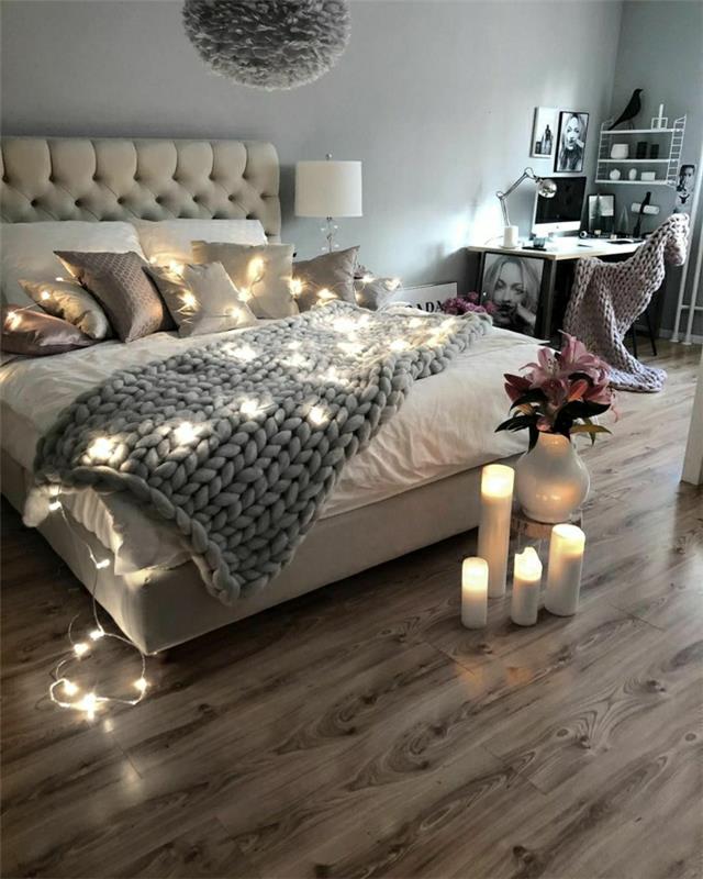 lentų grindys, jauki hygge stiliumi dekoruota lova, led žvakės, paminkštintas galvūgalis, mažas skandinaviškas stalas