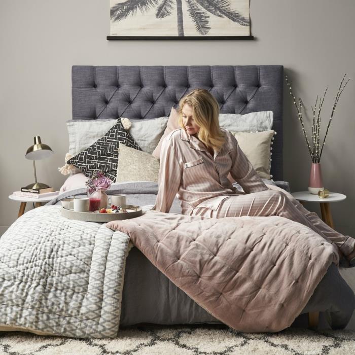 peleninė rožinė antklodė ir berberų kilimas kokonavimo kambaryje, moteris savo lovoje, du apvalūs naktiniai staleliai