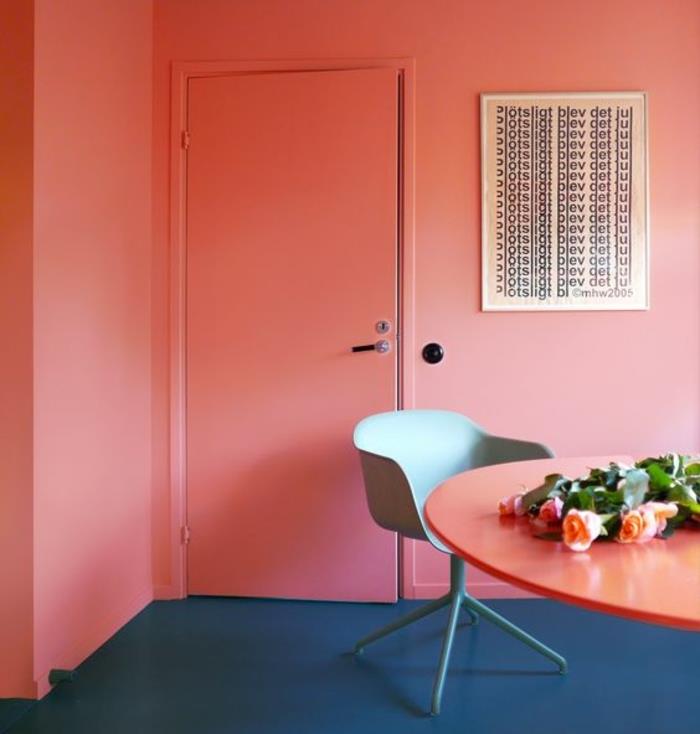 soba v marelični barvi, velika koralna miza, svetlo siv stol in tla v modri barvi