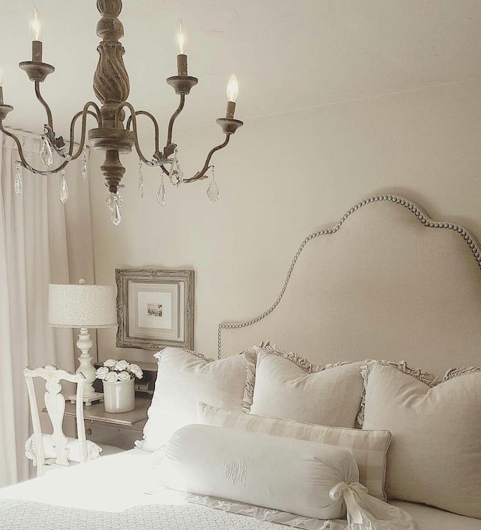 svetlo siva spalnica z belimi stenami, eleganten lestenec, sivo -belo posteljnina, eleganten lestenec v baročnem slogu, beli stol in lesena miza