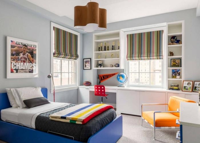 velika postelja z modrim okvirjem, oranžni naslanjač, ​​pisalna miza z belim skladiščem, športna fotografija, zavese za čolne