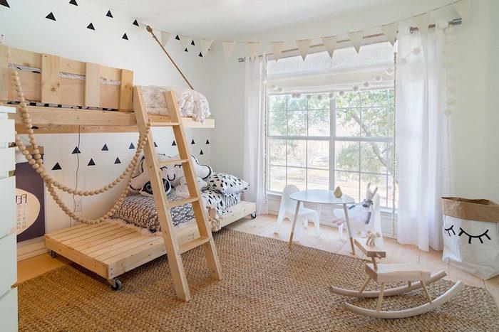Skandinaviškos tematikos vaikų kambarys su medine pakabinama lova ir baltomis sienomis