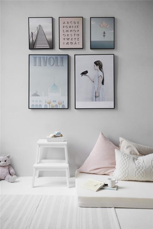 Çerçeveli sanat resimlerinden oluşan bir duvar galerisi ile İskandinav tarzında döşenmiş çocuk odası, elinde bir kuş tutan fotoğraf posteri kızı