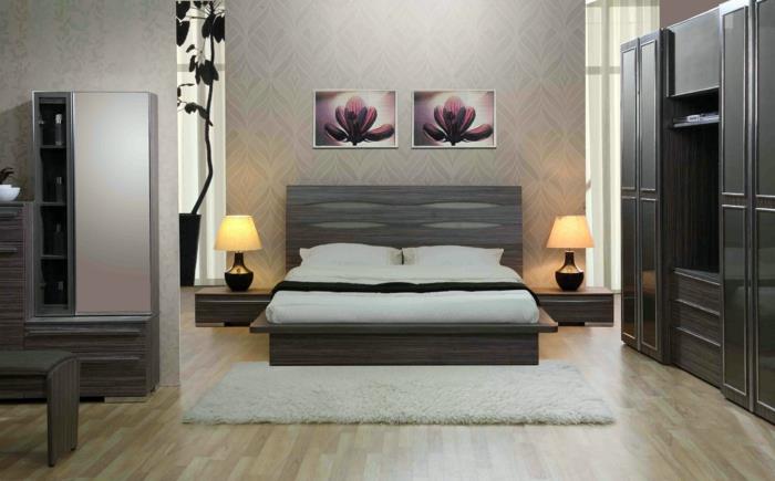 pilka lova, mažas kilimas, juoda drabužių spinta, du identiški paveikslai, dvi lempos prie lovos