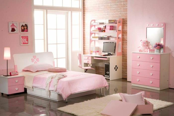 najstniška spalnica v roza in beli barvi, roza stene, rožnato pohištvo z ročaji v obliki belih srčkov, pravokotna preproga z dolgim ​​kupom, pisalna miza v beli in breskovi barvi