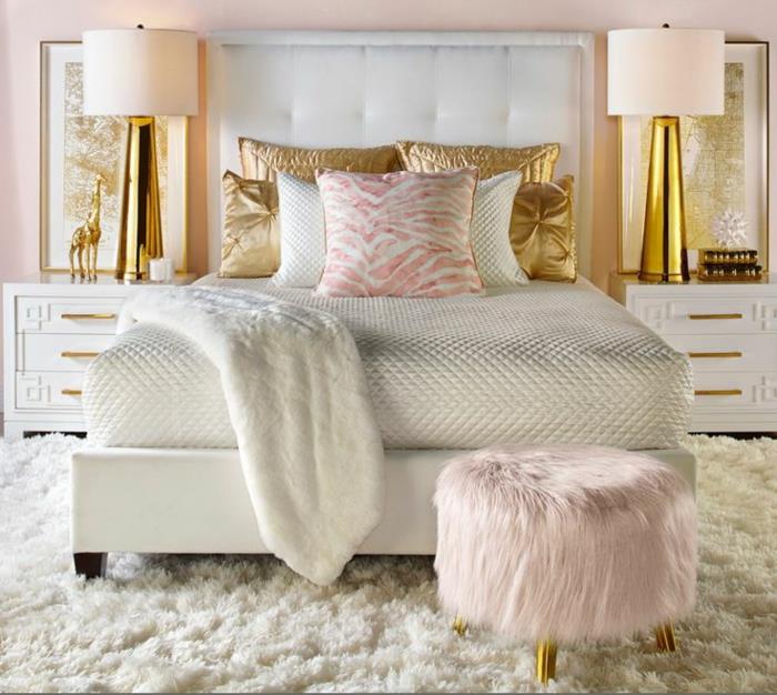 spalnica za odrasle bela deko, dlakavi stolček, rožnate in zlate blazine, belo vzglavje, zlate svetilke