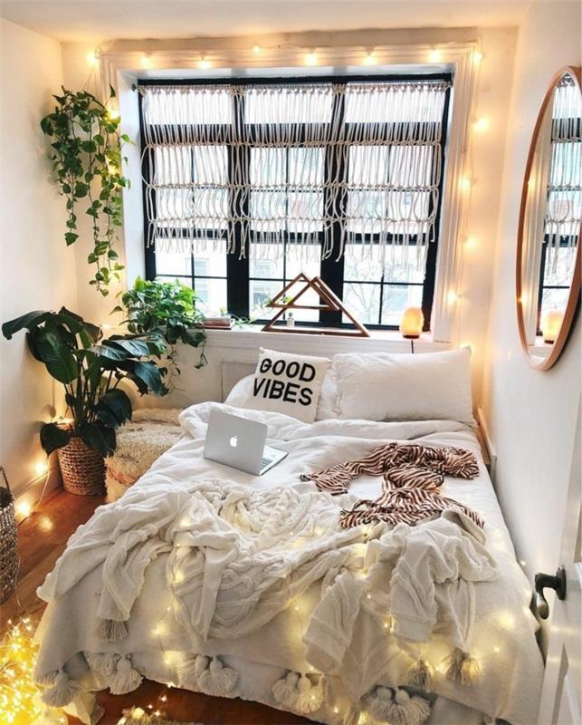 stebuklingas miegamojo dekoras, apvalus įrėmintas veidrodis, žali augalai, šviesi girlianda, pagalvėlė su raštu