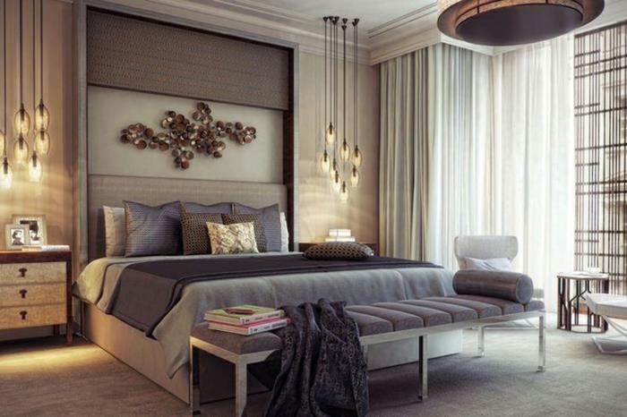 pakabinami žibintai, metalinis sienų dekoras, didelė pilka lova, didelis lubų šviestuvas, elegantiškas miegamasis