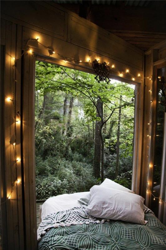 bohemiško miegamojo dekoras, didelis langas, žalios lovos metimas, šviesi girlianda