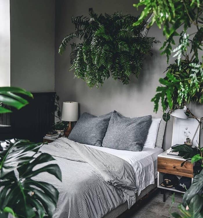 dekoracija spalnice v džungli v več zelenih rastlinah, monstera deliciosa in rastlina kot izvirno vzglavje, sivo -belo hišno perilo, sive stene