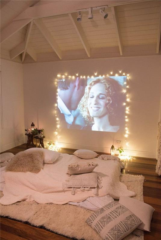 romantiškas miegamojo dekoras, privatus kinas, rožinė patalynė, baltos sijos lubos, dekoras su žibintais