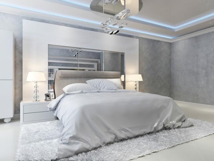 baltas ir pilkas miegamojo dekoras su šiuolaikišku pojūčiu, pilka galvūgalis, šviesios lubos, minkštas kilimas