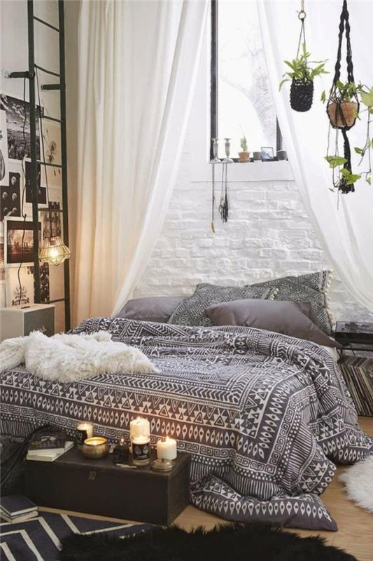 beyaz boyalı çıplak tuğla duvar, oryantal bir yatak odasında boho şık yatak, mumlu küçük vintage bavul