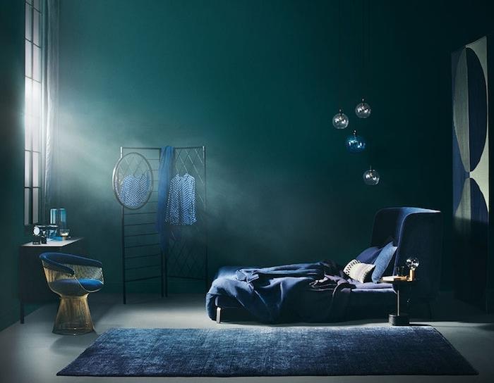 miegamojo idėja benzino ir tamsiai mėlynos spalvos, juodos spalvos tinklelis, tamsiai mėlyna lova ir kilimas, pilkos grindys, dizainerio fotelis, dramatiškas dekoras