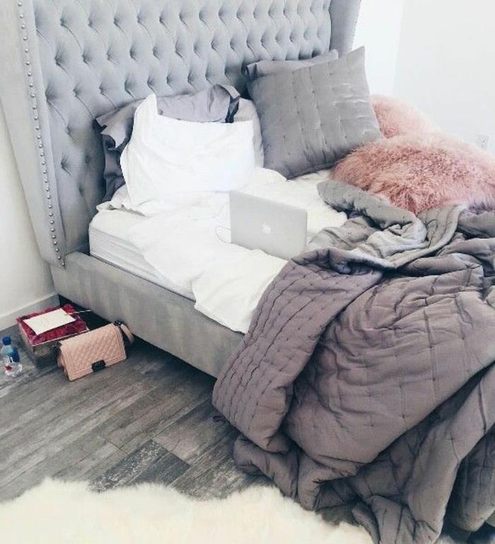 roza in siva spalnica, siva postelja z oblazinjenim vzglavjem, sivi leseni parket, bela preproga, rožnato, belo in sivo posteljnina, dekoriranje spalnice