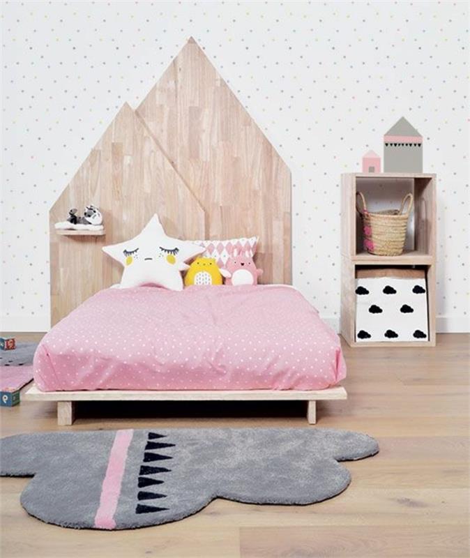 roza in siva spalnica, geometrijska lesena vzglavja, siva oblačna preproga, majhna lesena polica