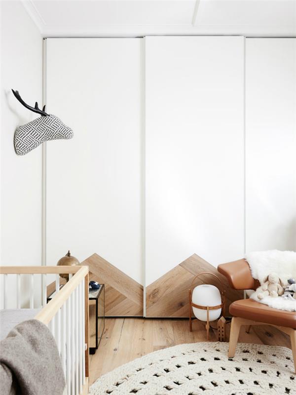 tipiškas deko pavyzdys skandinaviškam kūdikių kambariui su baltomis sienomis ir medžiu