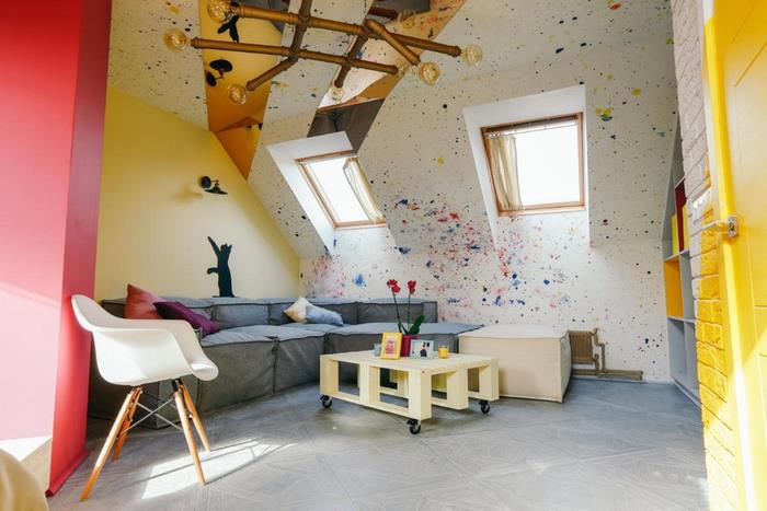 duvarlarda parlak renk vurguları ve palet sehpalı İskandinav tarzı mobilyalarla modern ve sanatsal çatı katı yatak odası düzeni