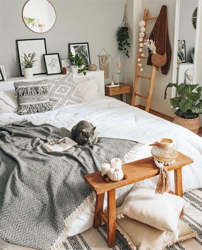 bohemiško stiliaus miegamasis balta patalynė pilka antklodė nuotraukų rėmeliai šviesūs mediniai baldai baltos ir pilkos pagalvėlės