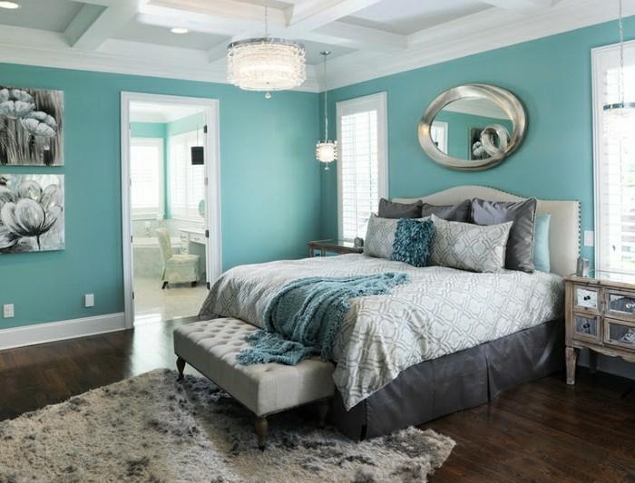 modra dekoracija spalnice za odrasle, parket iz temnega lesa, ovalno ogledalo, beli naslanjač